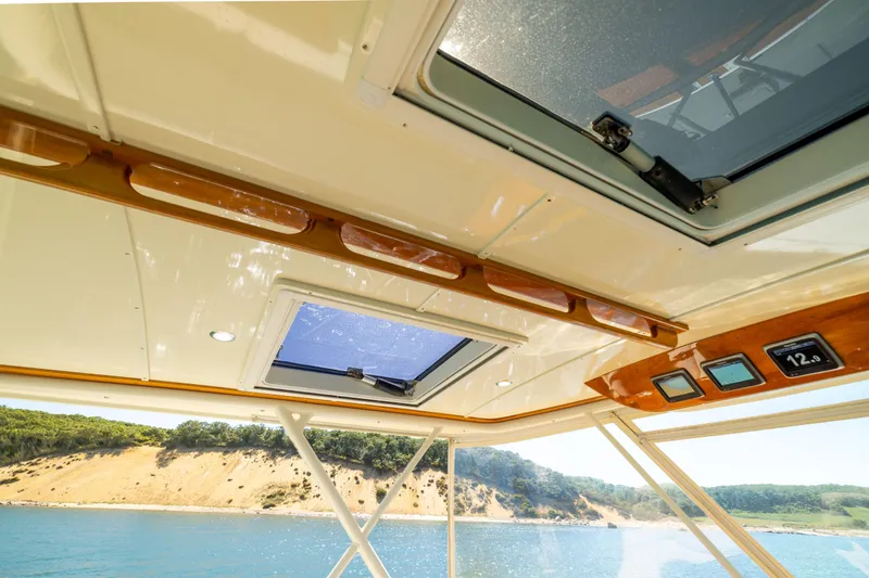 Barefoot Yacht Photos Pics 2014 Hinckley Talaria 48 Flybridge interior with skylight, overlooking scenic coastal view.
