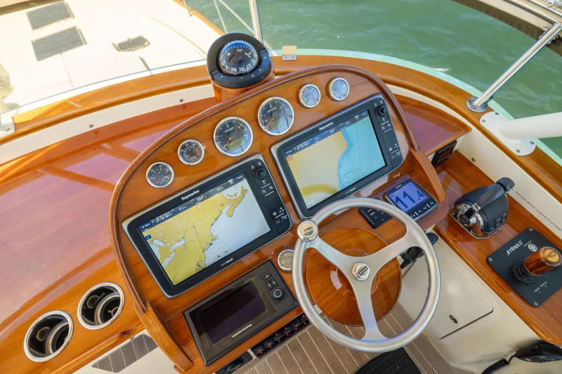 Barefoot Yacht Photos Pics Helm of 2014 Hinckley Talaria 48 Flybridge with navigation screens and wooden steering wheel.
