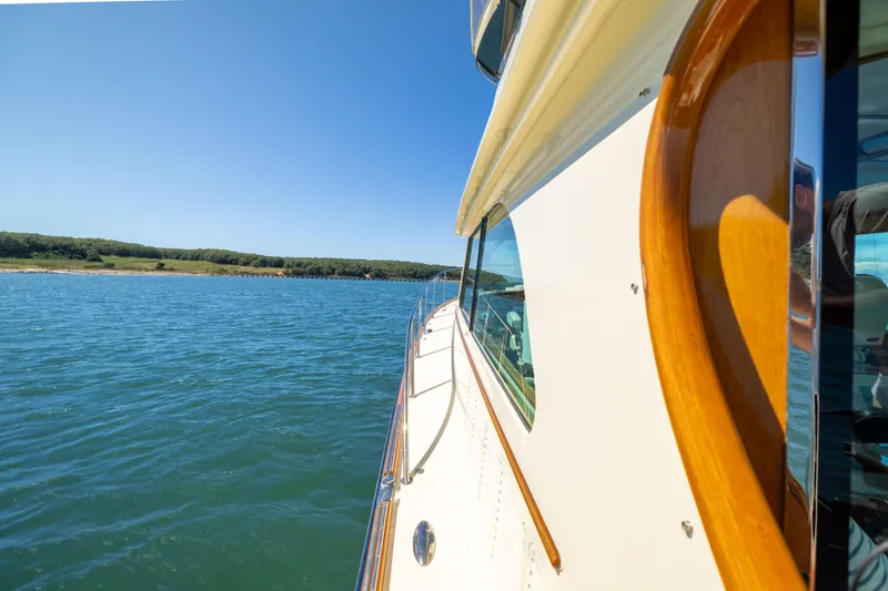 Barefoot Yacht Photos Pics 2014 Hinckley Talaria 48 Flybridge cruising on a sunny day, near a scenic shoreline.