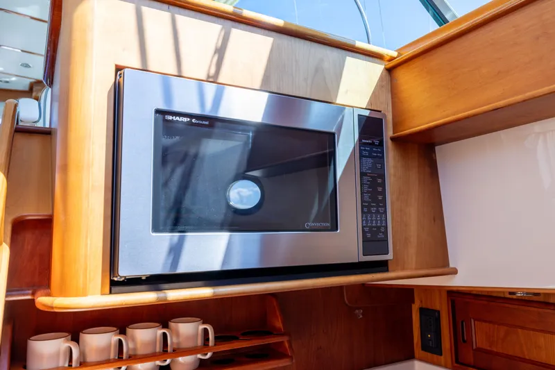 Barefoot Yacht Photos Pics Microwave in 2014 Hinckley Talaria 48 Flybridge yacht kitchen, with wooden cabinetry and mugs.