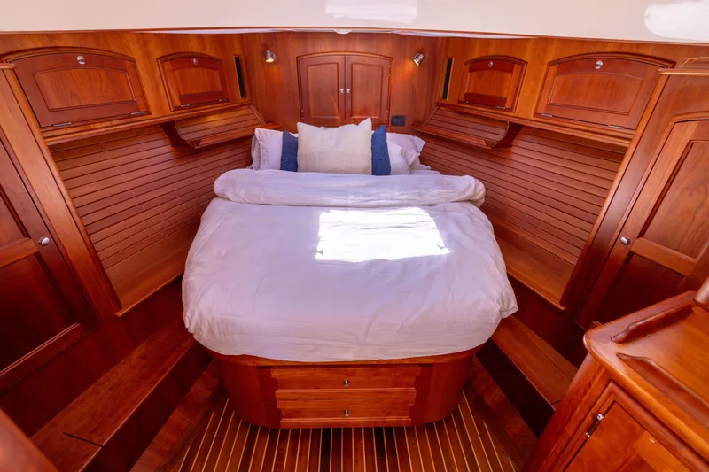 Barefoot Yacht Photos Pics Luxurious 2014 Hinckley Talaria 48 Flybridge cabin with elegant wood finish and cozy bedding.