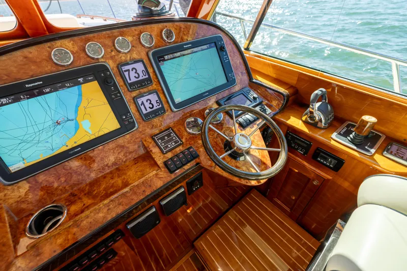 Barefoot Yacht Photos Pics Helm of 2014 Hinckley Talaria 48 Flybridge with navigation screens and wooden steering wheel.