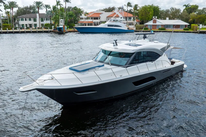 Sapphire Yacht Photos Pics 2022 Riviera 575 SUV yacht cruising on a scenic waterfront with luxury homes.