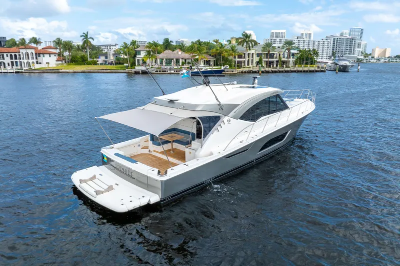 Sapphire Yacht Photos Pics 2022 Riviera 575 SUV yacht cruising on a scenic waterfront with luxury homes.