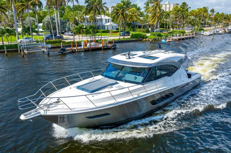 Sapphire Yacht Photos Pics 2022 Riviera 575 SUV cruising on a scenic waterway with palm trees in the background.