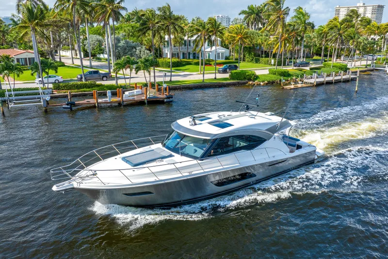 Sapphire Yacht Photos Pics 2022 Riviera 575 SUV cruising on a scenic waterway with palm trees.