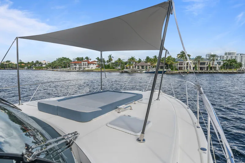 Sapphire Yacht Photos Pics 2022 Riviera 575 SUV yacht with sunshade, cruising near luxury waterfront homes.