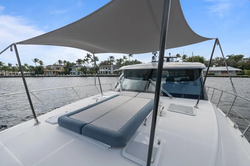 Sapphire Yacht Photos Pics 2022 Riviera 575 SUV yacht with sunshade and deck view on a serene waterway.