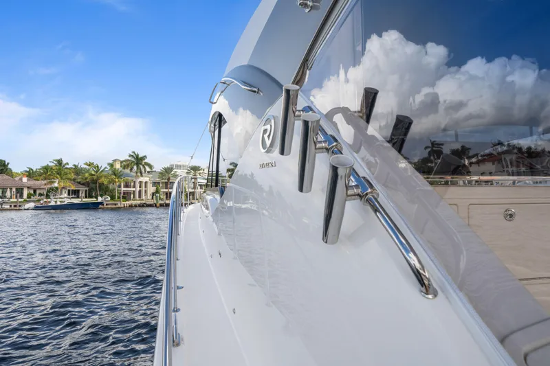 Sapphire Yacht Photos Pics 2022 Riviera 575 SUV yacht on water, reflecting sky and clouds.