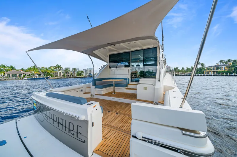 Sapphire Yacht Photos Pics 2022 Riviera 575 SUV yacht with spacious deck, docked by waterfront homes.