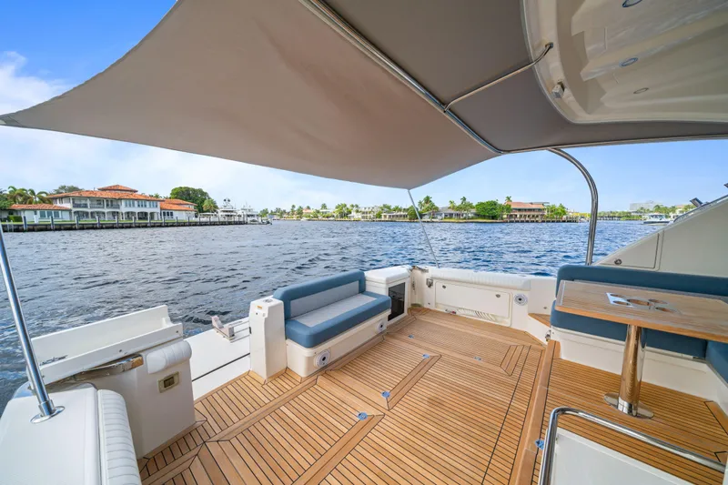 Sapphire Yacht Photos Pics Luxurious 2022 Riviera 575 SUV yacht deck with seating, table, and waterfront view.