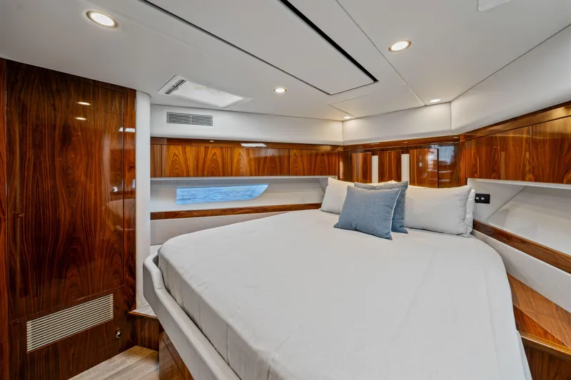 Sapphire Yacht Photos Pics Luxurious bedroom interior of 2022 Riviera 575 SUV yacht with wood paneling and plush bedding.