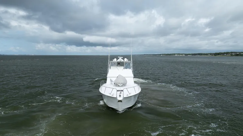 Wet Hooker Yacht Photos Pics 2003 Hatteras 60 Convertible yacht cruising on open water under cloudy skies.