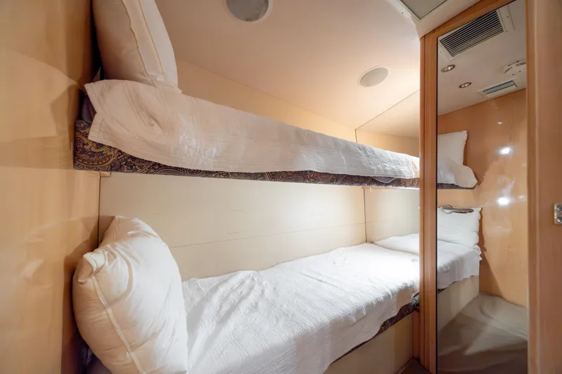 Wet Hooker Yacht Photos Pics Bunk beds in 2003 Hatteras 60 Convertible yacht cabin, featuring cozy bedding and wood paneling.