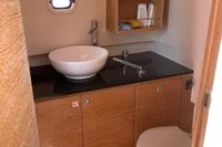 Modern bathroom in 2012 Fjord 36' Open yacht with sink, toilet, and wooden cabinetry.