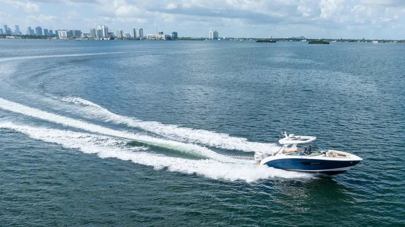 Poly Yacht Photos Pics 2019 Regal 33 OBX boat cruising on open water with city skyline in background.