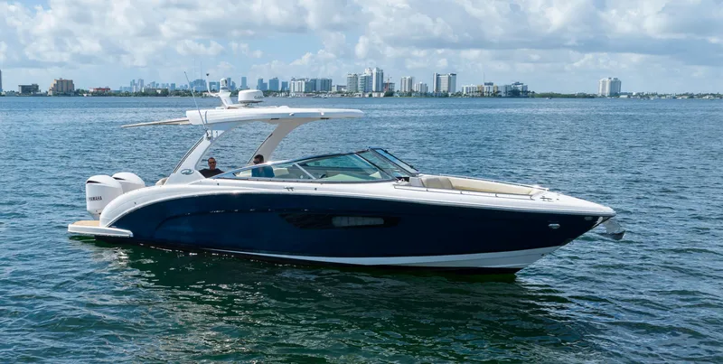 Poly Yacht Photos Pics 2019 Regal 33 OBX boat cruising on a calm sea with city skyline in background.