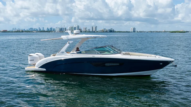 Poly Yacht Photos Pics 2019 Regal 33 OBX boat cruising on a sunny day with city skyline in background.