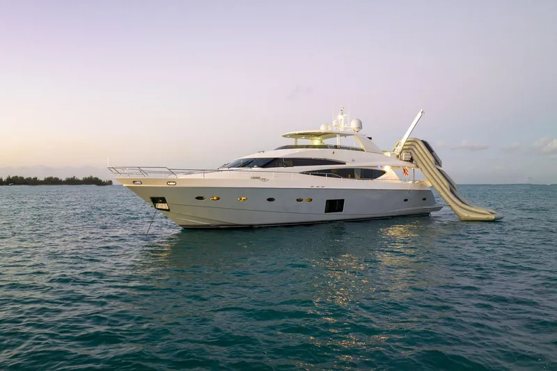 Current Sea Yacht Photos Pics Luxurious 2011 Princess 95 yacht with slide, anchored in serene waters at sunset.