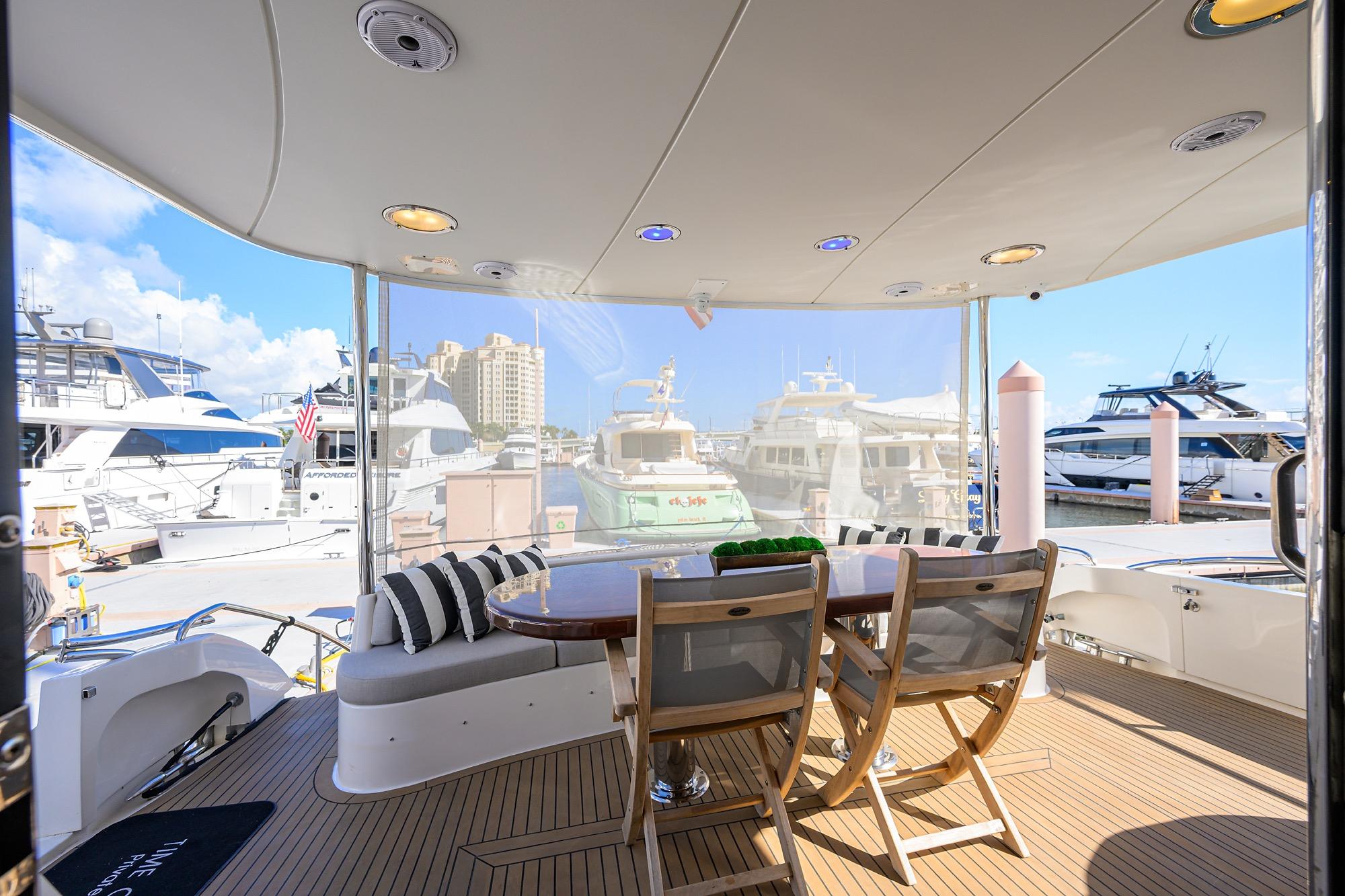 Luxurious 2005 Lazzara 68 Enclosed Bridge yacht with elegant outdoor seating at marina.