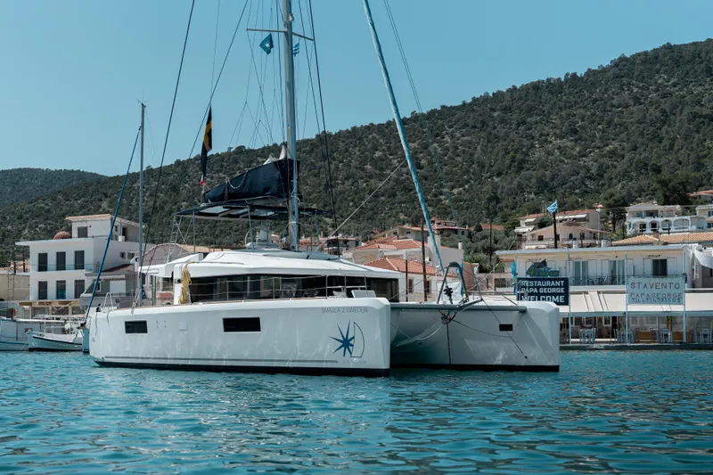  Yacht Photos Pics 2018 Lagoon 52 F catamaran docked in a scenic harbor with hillside backdrop.