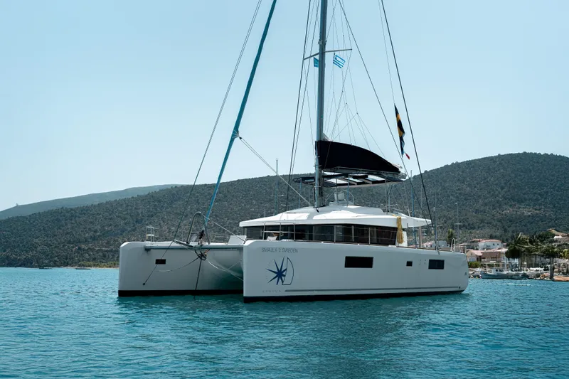  Yacht Photos Pics 2018 Lagoon 52 F catamaran sailing on calm waters with scenic hills in the background.