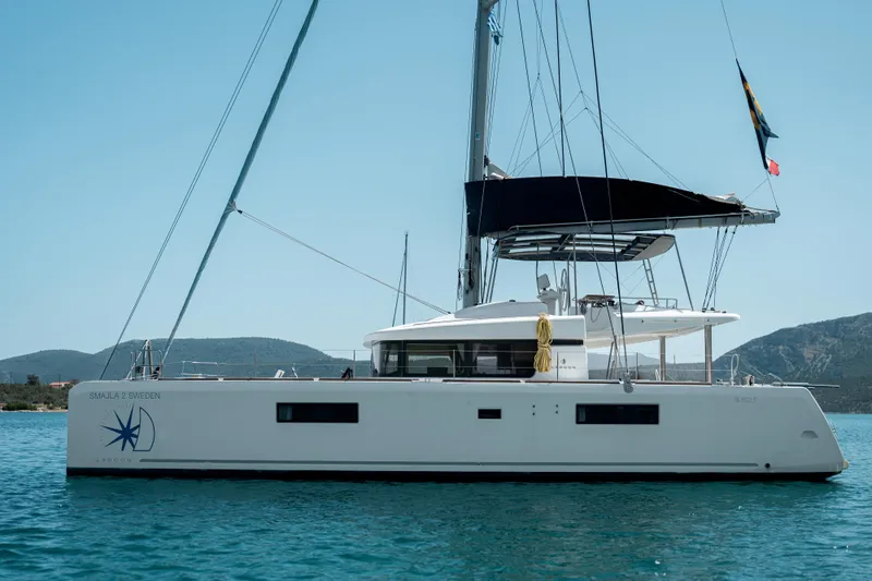  Yacht Photos Pics 2018 Lagoon 52 F catamaran sailing on calm waters with scenic mountain backdrop.