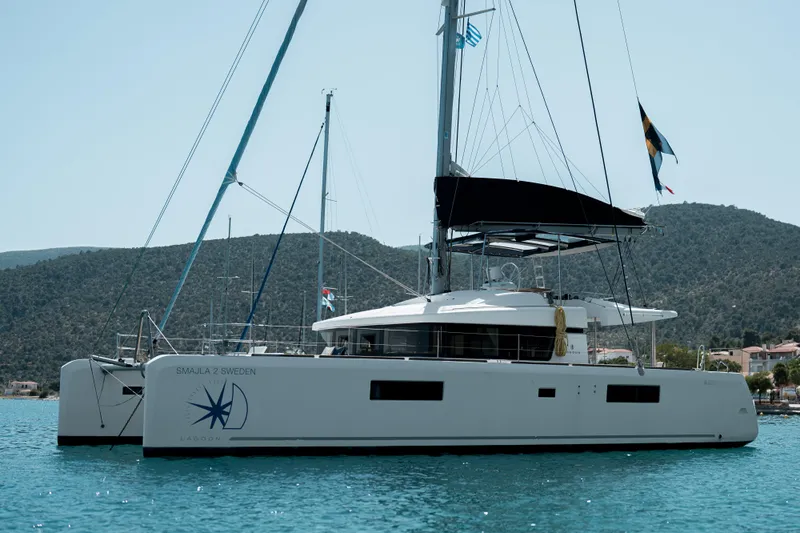  Yacht Photos Pics 2018 Lagoon 52 F catamaran sailing on calm waters with scenic mountain backdrop.