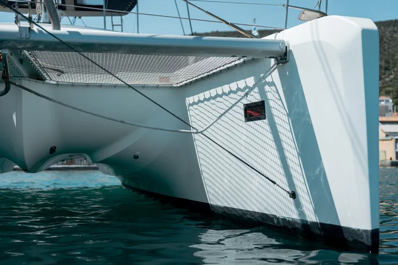  Yacht Photos Pics 2018 Lagoon 52 F catamaran, close-up of hull and netting, docked in calm waters.