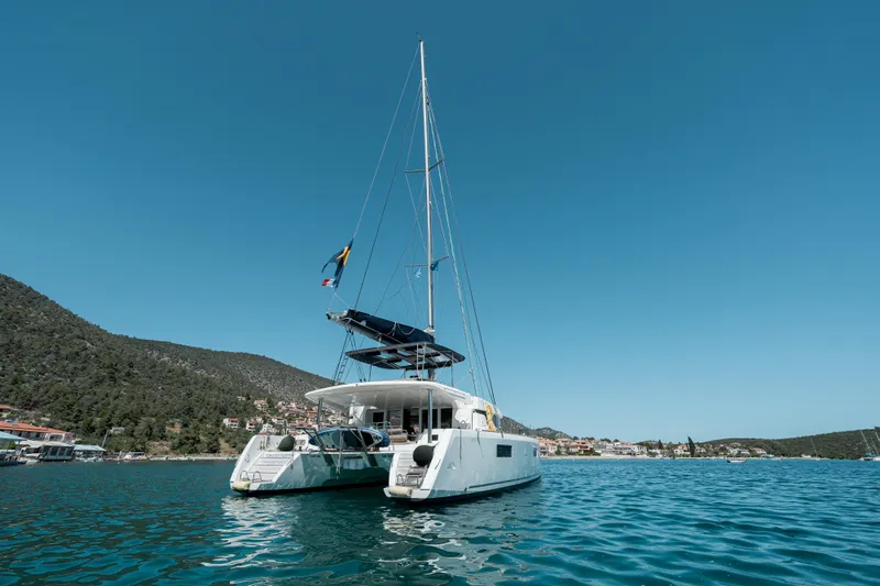  Yacht Photos Pics 2018 Lagoon 52 F catamaran sailing in a scenic coastal area.