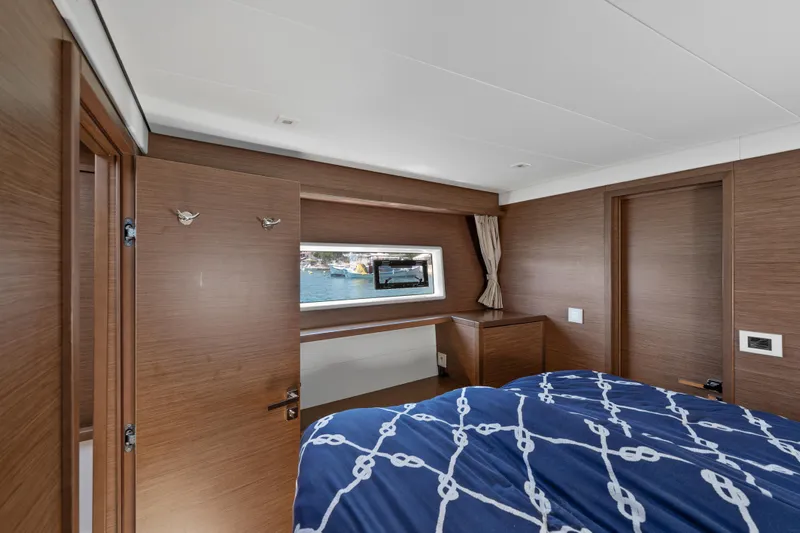  Yacht Photos Pics Luxurious cabin interior of 2018 Lagoon 52 F yacht with wood finish and nautical bedding.