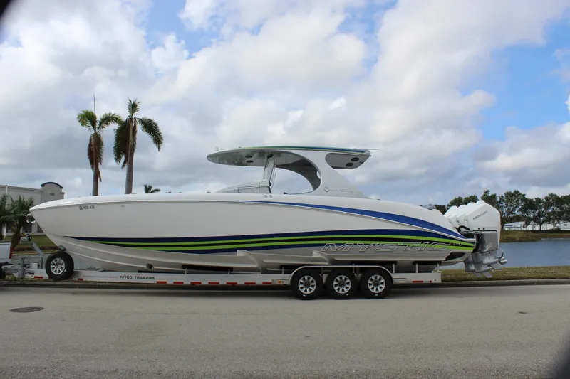  Yacht Photos Pics 2020 Mystic Powerboats M4200 on trailer, sleek design, vibrant stripes, parked by waterfront.