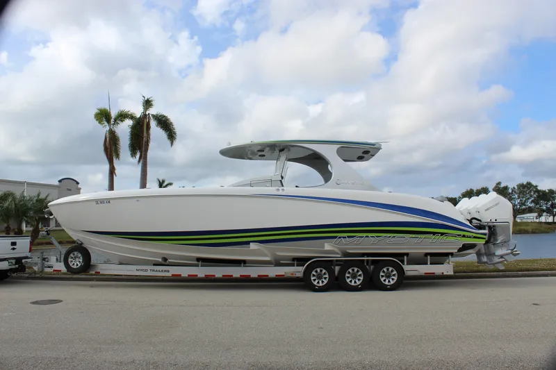  Yacht Photos Pics 2020 Mystic Powerboats M4200 on trailer, sleek design with vibrant accents, parked by palm trees.