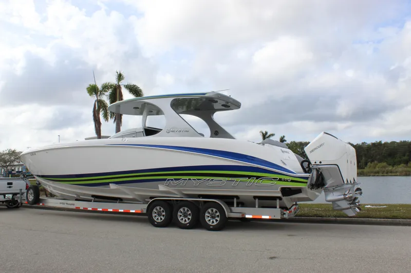  Yacht Photos Pics 2020 Mystic Powerboats M4200 on trailer by a lake, featuring sleek design and vibrant graphics.