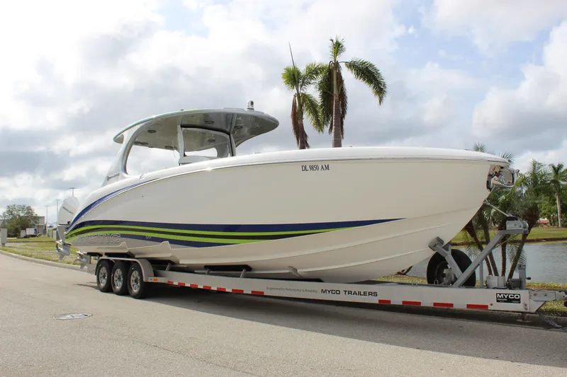  Yacht Photos Pics 2020 Mystic Powerboats M4200 on trailer, parked near palm trees and waterway.