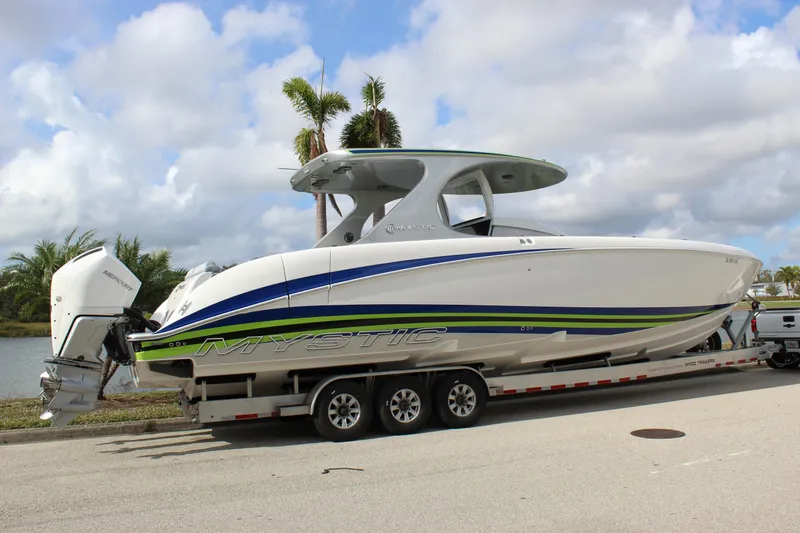  Yacht Photos Pics 2020 Mystic Powerboats M4200 on trailer, sleek design with vibrant accents, parked by palm trees.