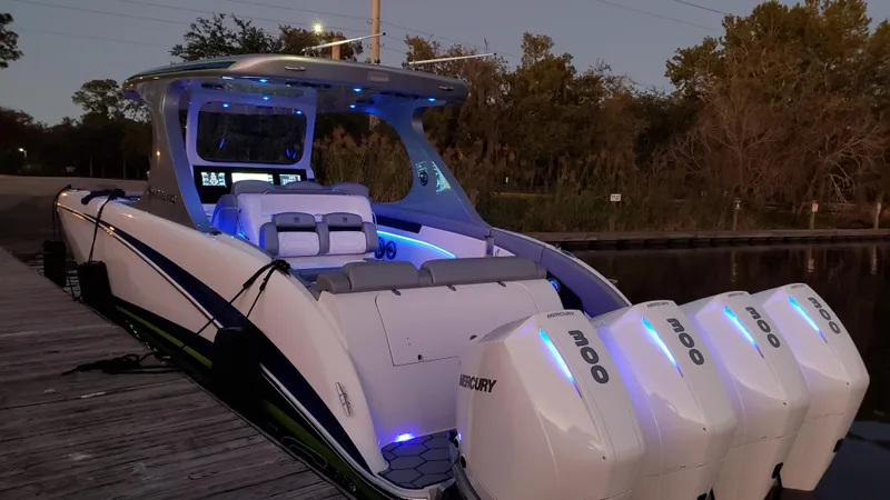  Yacht Photos Pics 2020 Mystic Powerboats M4200 with illuminated interior and four Mercury engines docked at sunset.