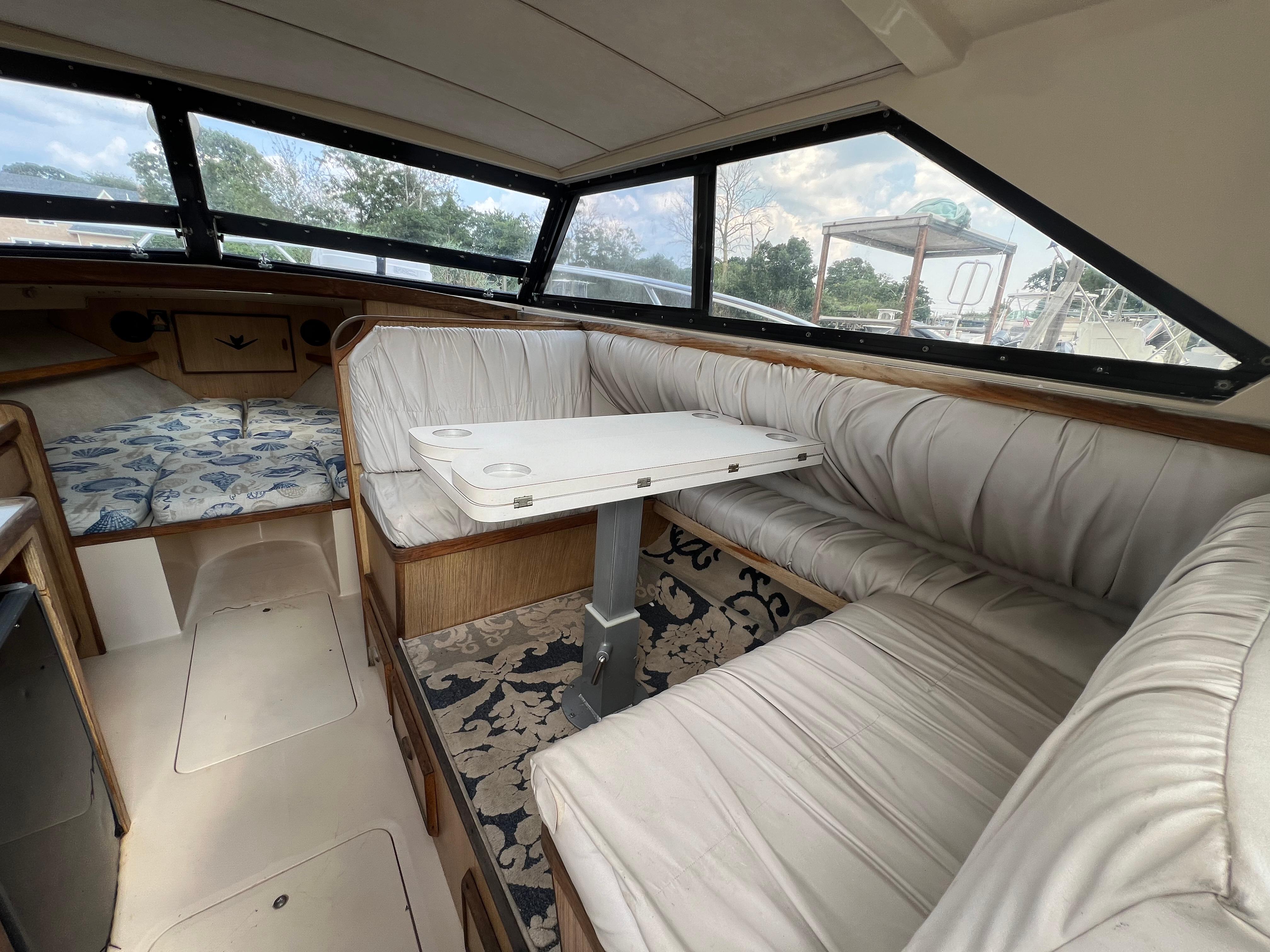 Interior of a 1990 Bertram 28 Flybridge boat with cushioned seating and table.
