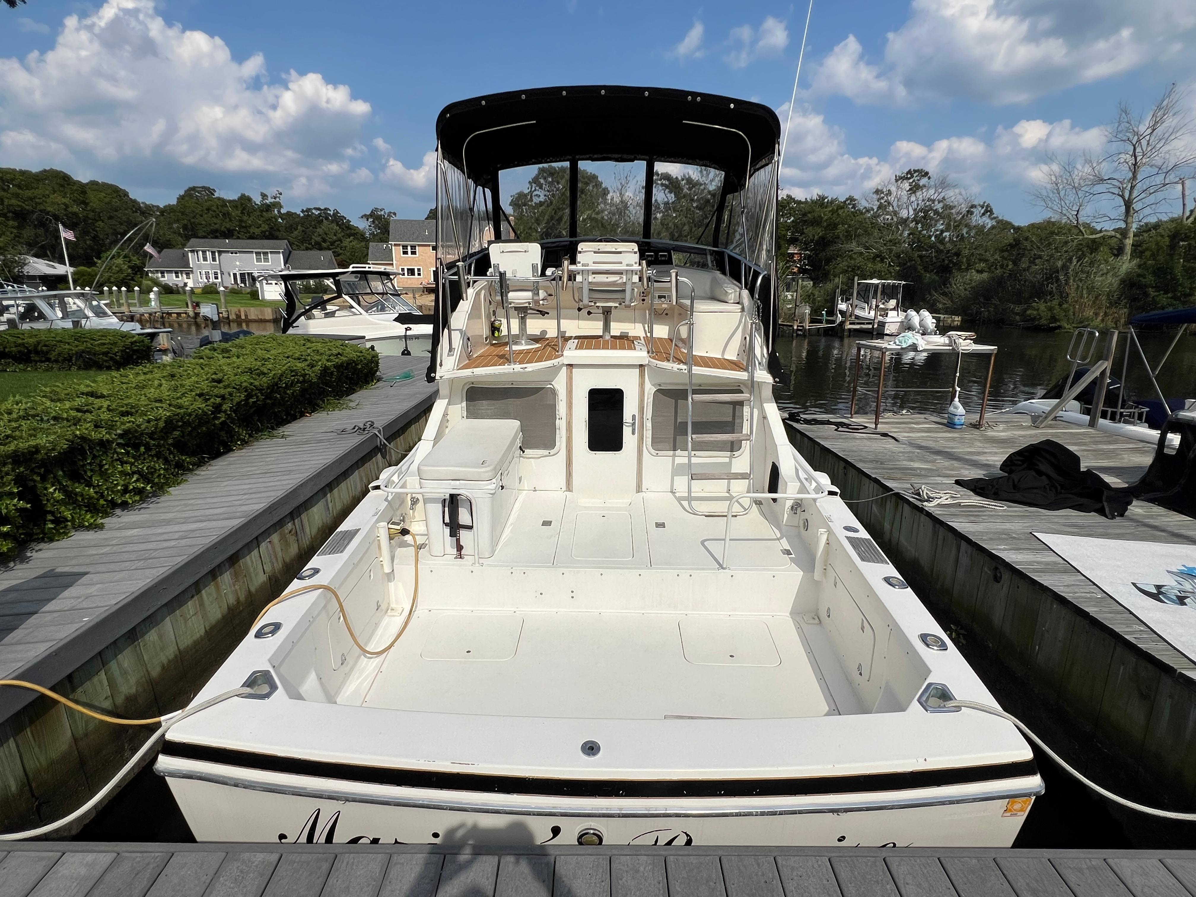 1990 Bertram 28 Flybridge boat docked, featuring spacious deck and flybridge under clear skies.