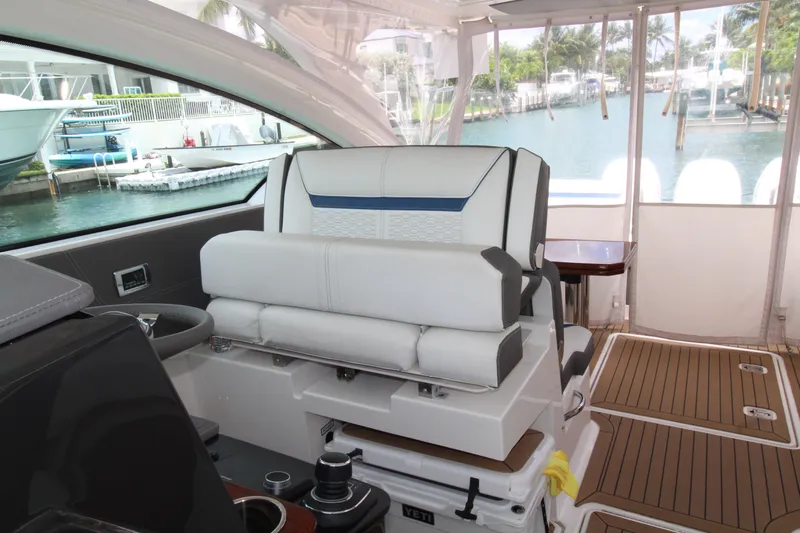 Knot Sorry Yacht Photos Pics 2021 Tiara Yachts 38LX interior with helm seat, wooden flooring, and marina view.