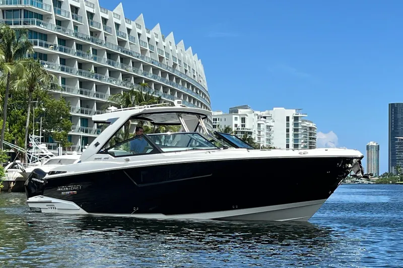  Yacht Photos Pics 2023 Monterey 385 Super Sport boat cruising near modern waterfront buildings.