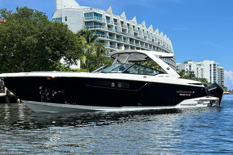  Yacht Photos Pics 2023 Monterey 385 Super Sport boat on water, modern buildings in background.