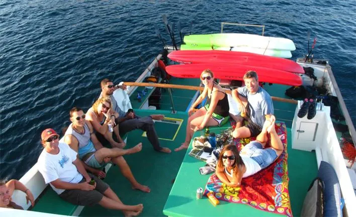 Truth Yacht Photos Pics Group relaxing on 1974 Custom Expedition Liveaboard boat with kayaks, enjoying sunny day at sea.
