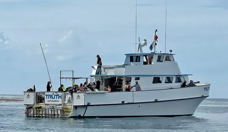 Truth Yacht Photos Pics Custom 1974 Expedition Liveaboard boat with passengers, ocean backdrop, and diving platform.
