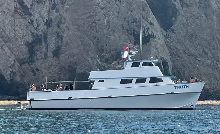 Truth Yacht Photos Pics Custom 1974 Expedition Liveaboard boat "Truth" anchored near rocky cliffs.