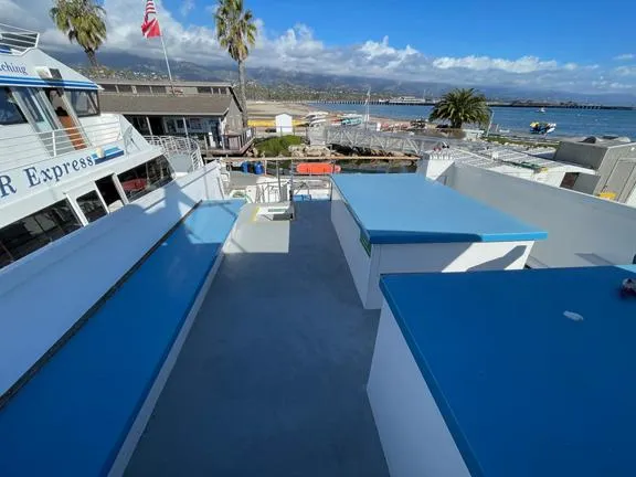 Truth Yacht Photos Pics Custom 1974 Expedition Liveaboard boat deck with blue benches, docked near palm trees and marina.