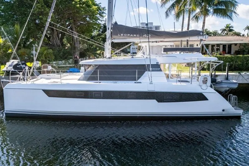 Panthera Yacht Photos Pics 2021 Leopard 42 catamaran docked by palm trees, showcasing sleek design and modern features.