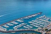 Aerial view of a marina with numerous boats docked, surrounded by calm blue waters.