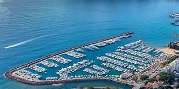 Aerial view of a marina with numerous boats docked, surrounded by calm blue waters.
