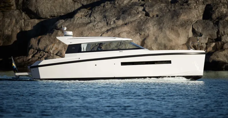  Yacht Photos Pics 2023 Delta Powerboats 33 Coupe cruising on water near rocky shoreline.